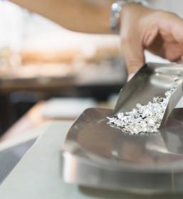A jeweller pours uncut diamonds onto a scale
