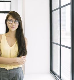 A young professional stands in an open plan office