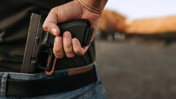 A man holds a gun behind his back as a car approaches