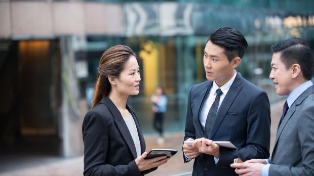 A group of three business managers have a serious discussion outside the office