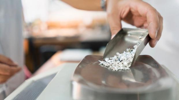 A jeweller pours particles of silver onto a scale
