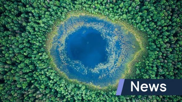 A view from above of a blue lake in a vibrant green forest