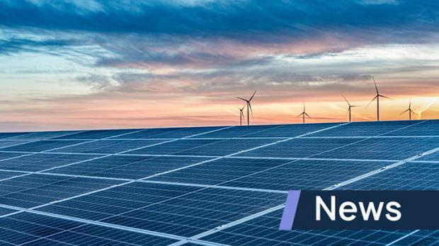 Solar panels during sunset with wind turbines in the distance