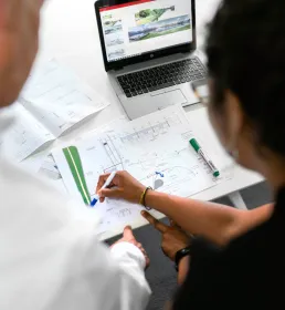 Two people looking at some technical plans