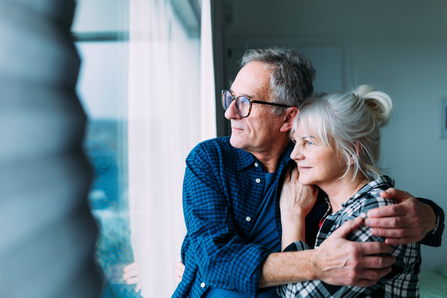 couple âgé regarde par la fenêtre