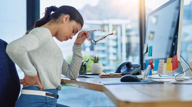 Une jeune femme travaillant dans un bureau souffre de mal de dos 