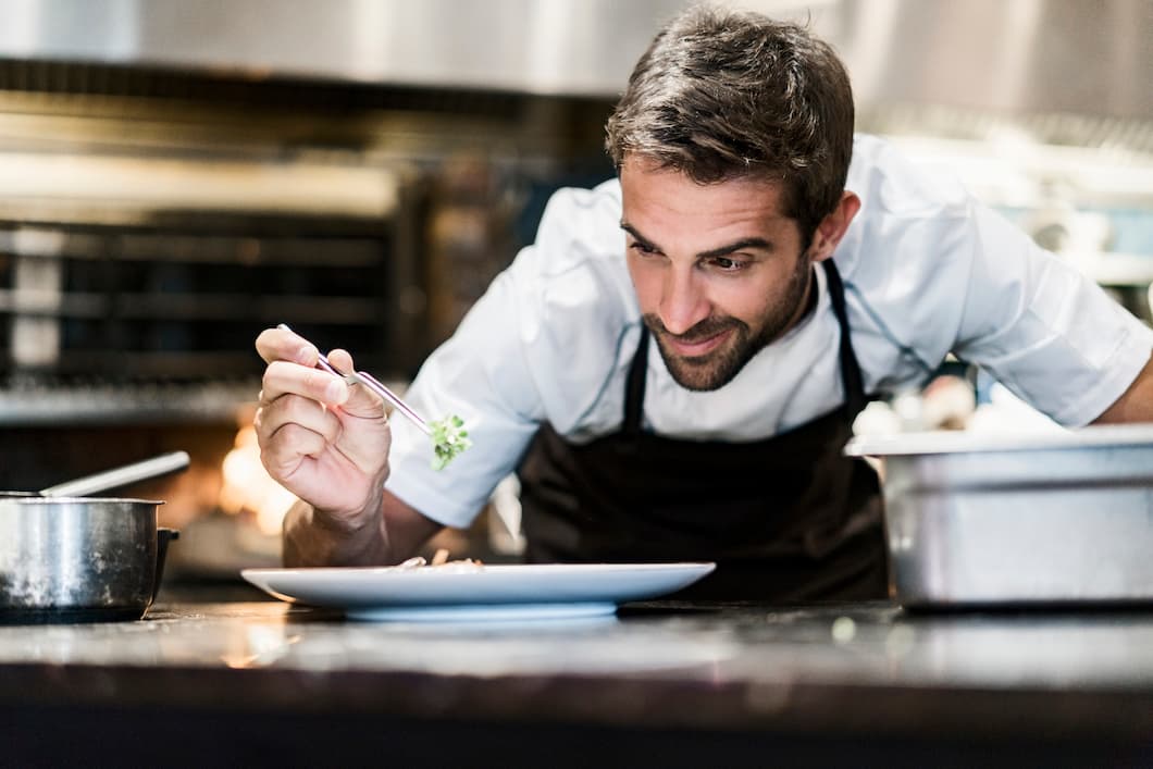 A chef garnishes a dish in a professional kitchen