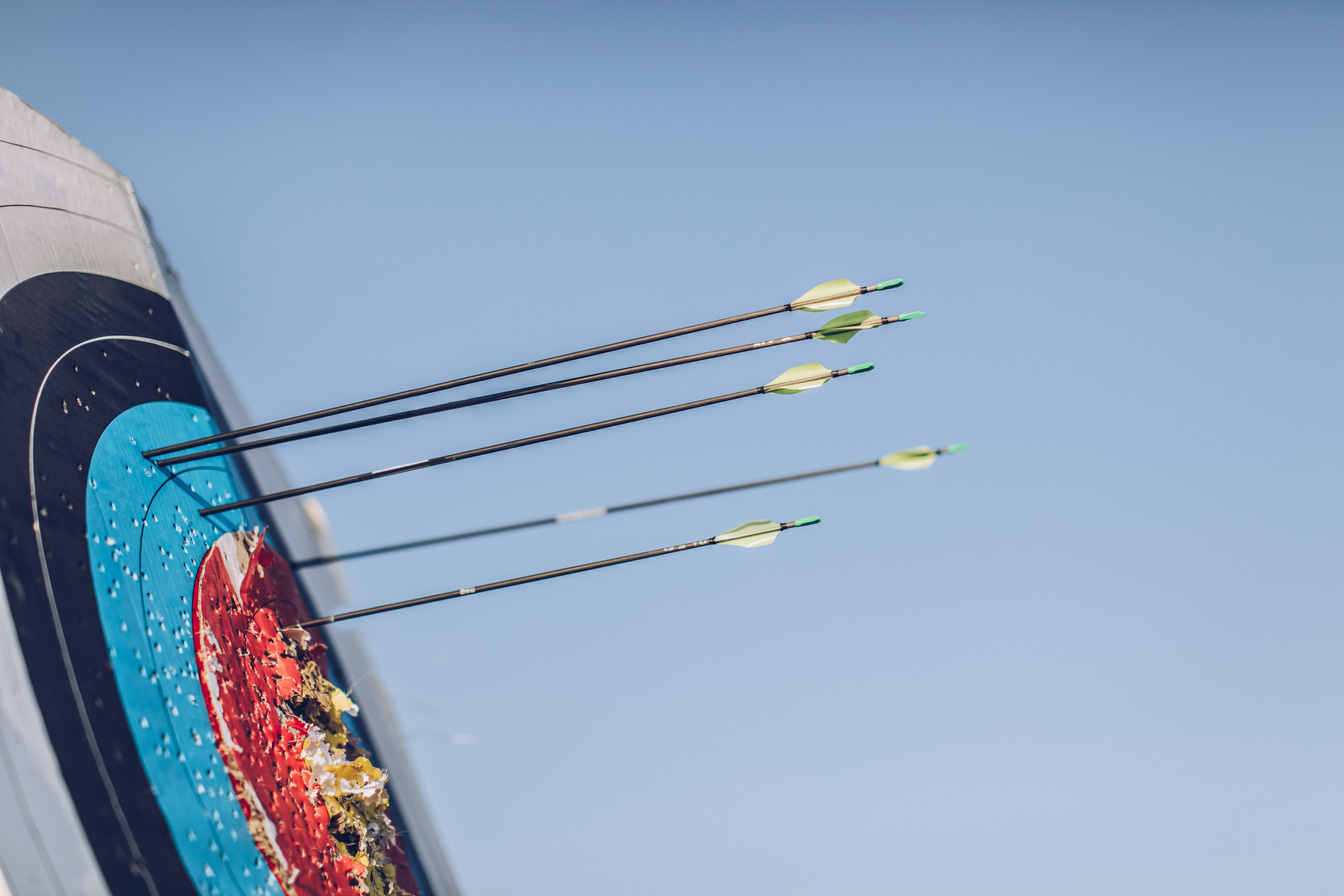 Archery arrows in target board blue sky
