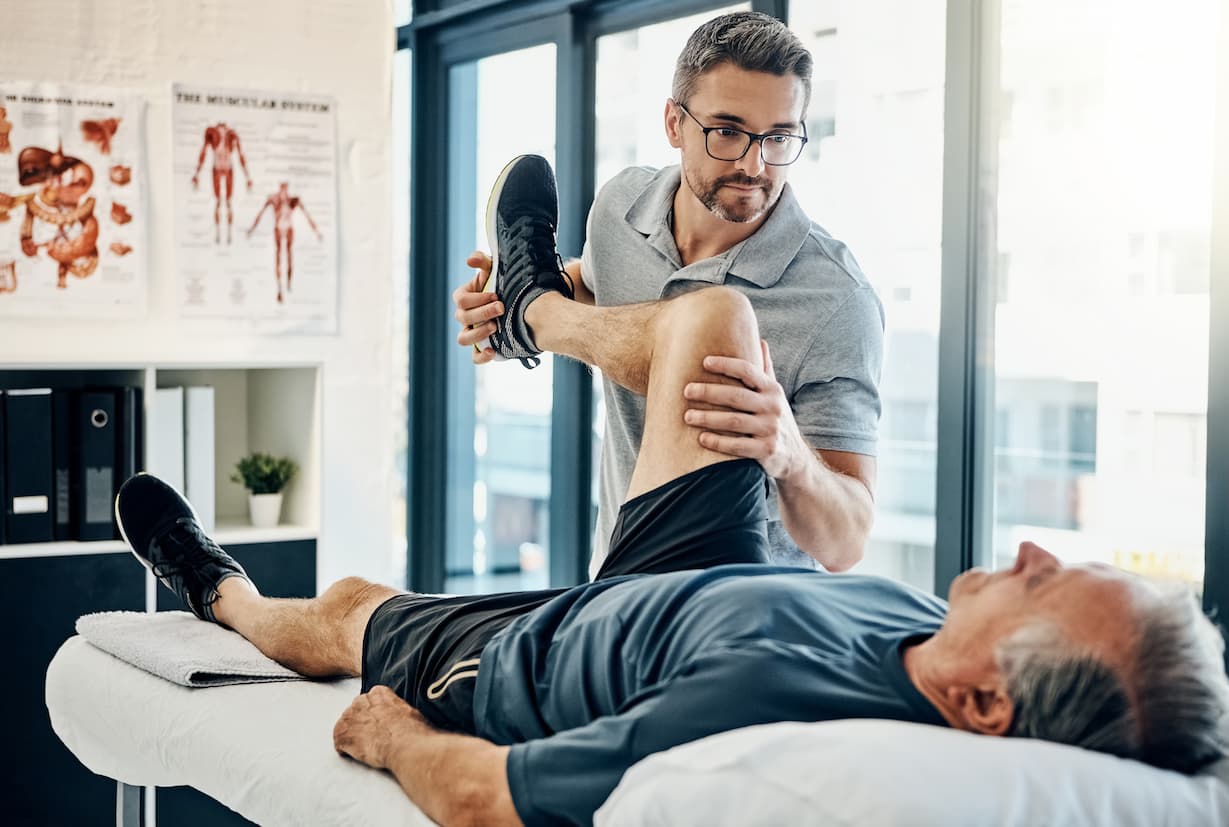 Physio flexing a patient's knee