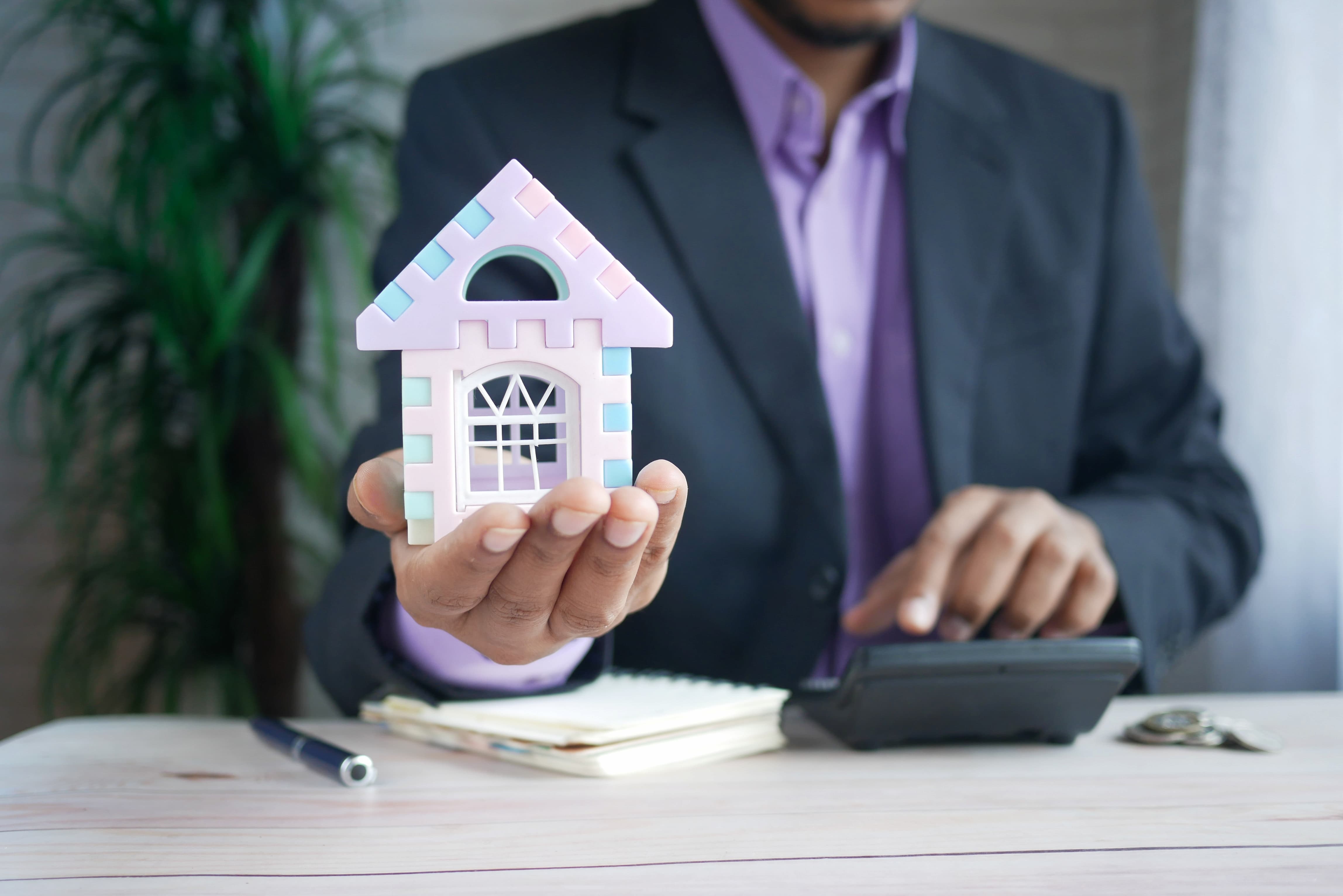 Estate agent holding miniature house in palm of hand