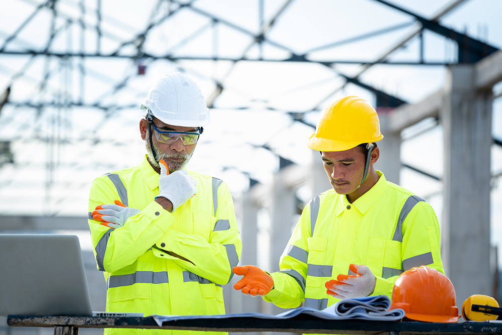 Two engineers in high-vis jackets looking at plans on a construction site