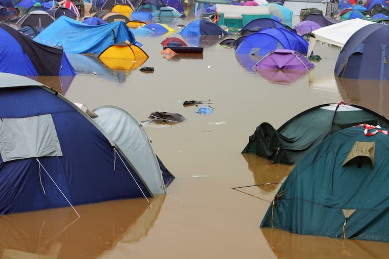 Tents sit in deep muddy flood water