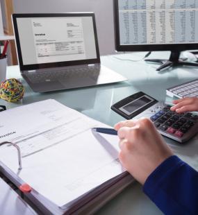 A financial adviser uses a calculator while reading through a folder of data