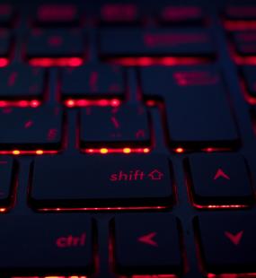 A close-up of a keyboard with red light glowing from under the keys