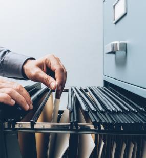 Hands move files in a filing cabinet