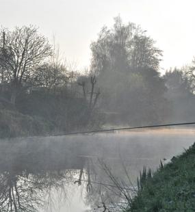 misty river bank with fisherman - angling trust federations insurance