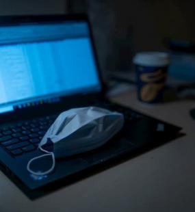 A face mask on laptop keyboard pandemic virus