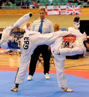 Two Taekwondo competitors throwing simultaneous kicks  