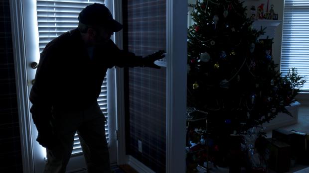 Burglar breaking in and creeping up to Christmas tree