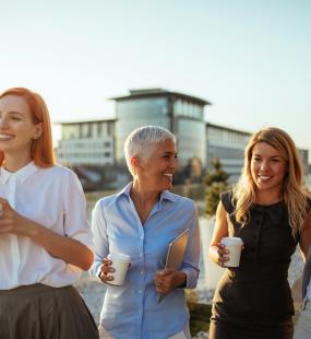 four female collegues drinking coffee and chatting laughing