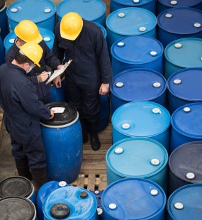 Two men inspecting a large amount of blue barrels