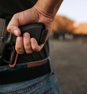A man holds a gun behind his back as a car approaches
