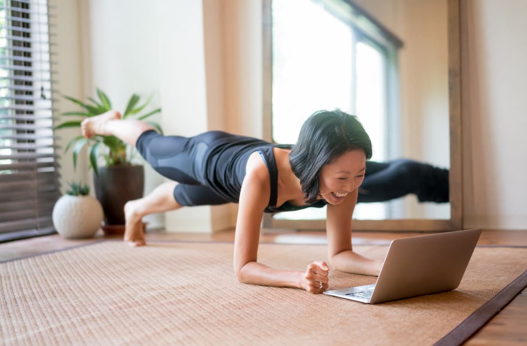 Woman doing yoga while looking at a laptop
