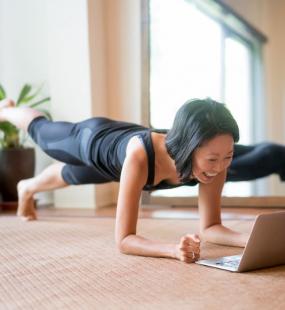 Woman doing yoga while looking at a laptop