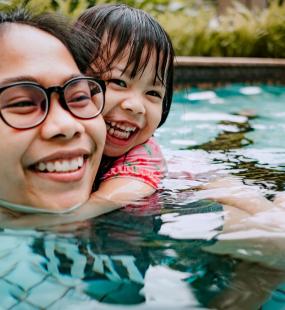 Smiling mother in pool with her daughter