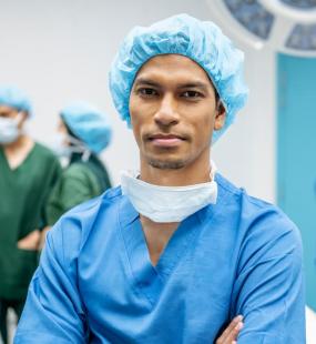 A surgeon in scrubs looking into the camera