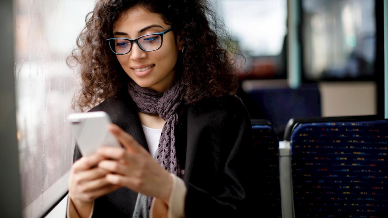 A woman uses her smart phone sitting by the window of a bus