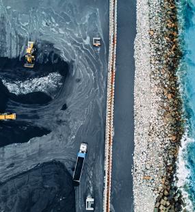 An aerial view of trucks moving coal by the coast