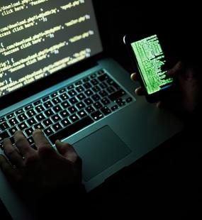 Cyber hacker looking at computer code