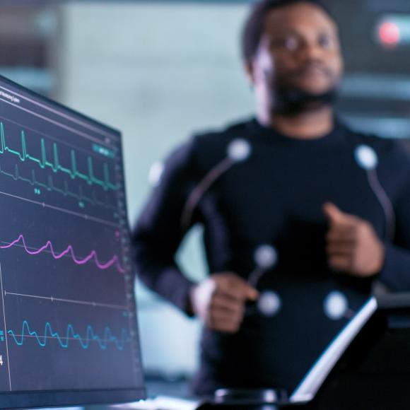 Man on on running machine with EKG data in foreground