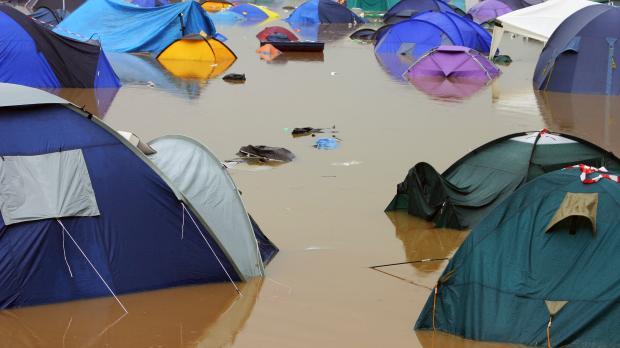 Tents sit in deep muddy flood water