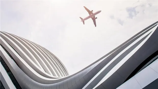 plane flying near modern building