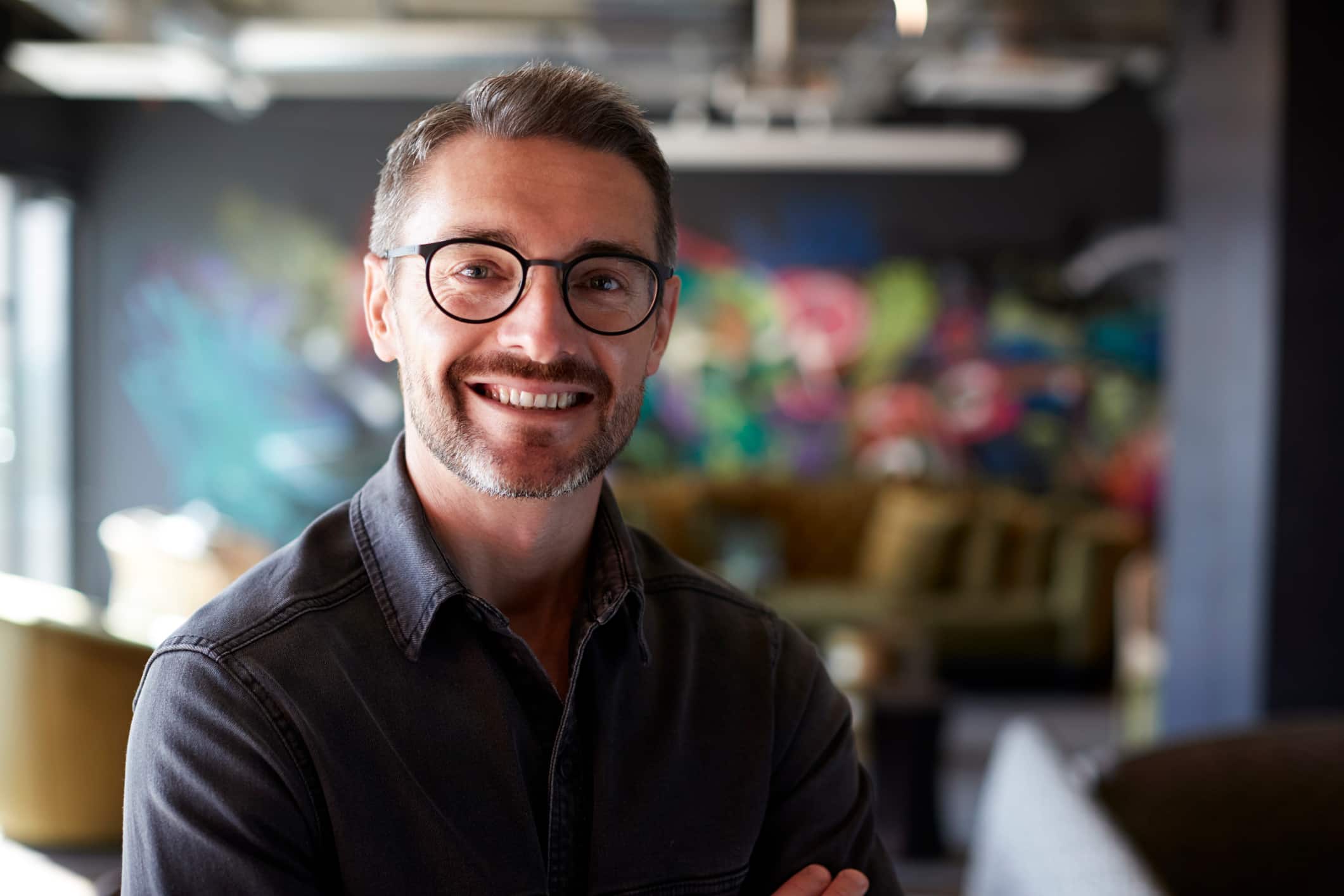 A creative businessman stands in a studio smiling at the camera