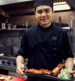 Chef proudly showing a plate of seafood