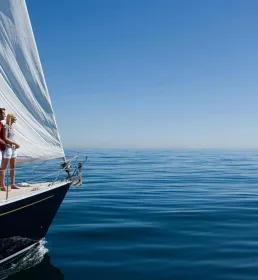 A couple stands on their private yacht looking out at the sea