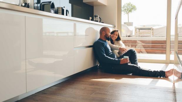 A couple sit on the floor of their luxury modern kitchen