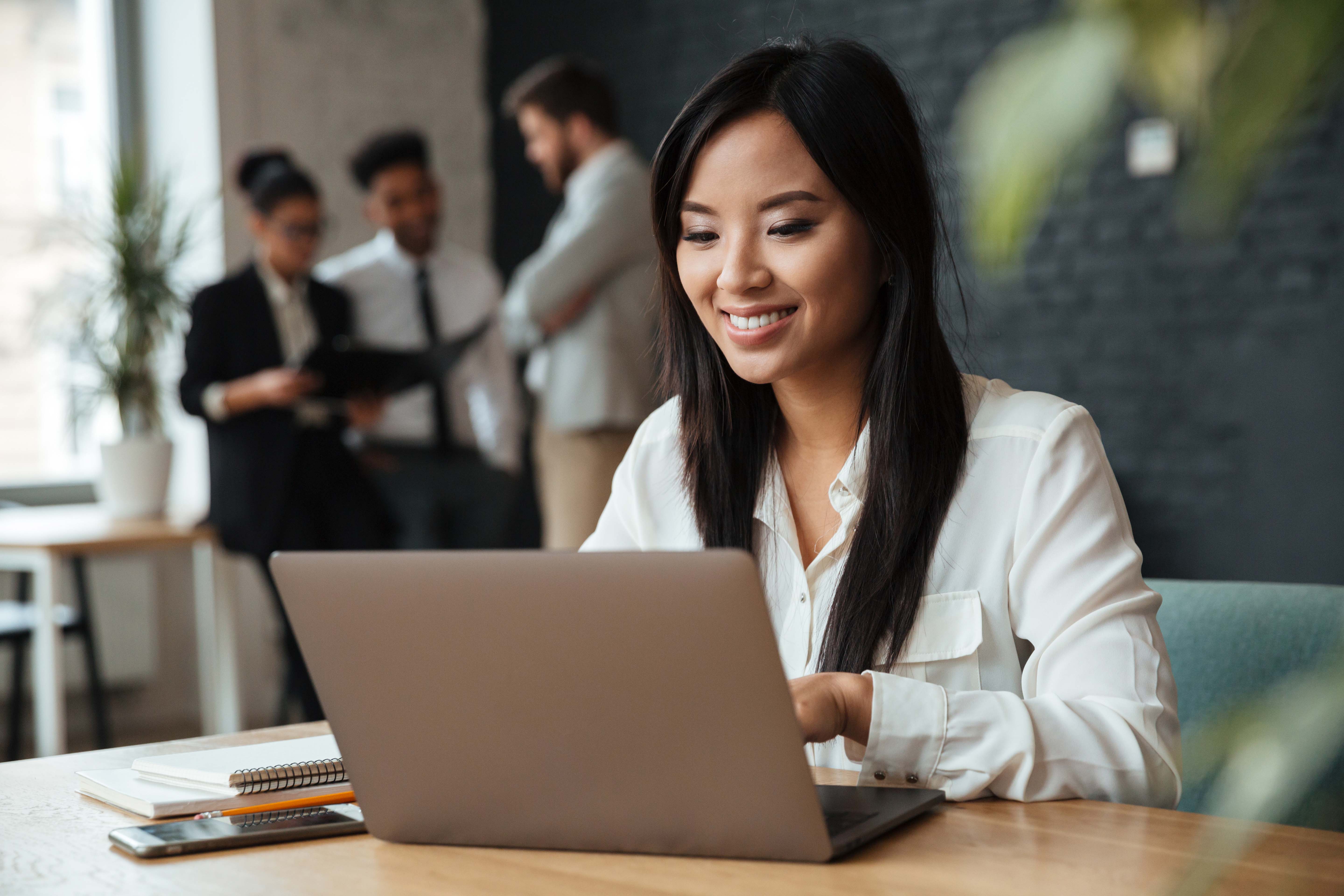Cheerful young Asian woman using laptop