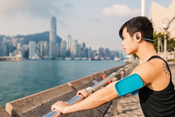 Man pausing after a run with Victoria Harbour skyline in the background