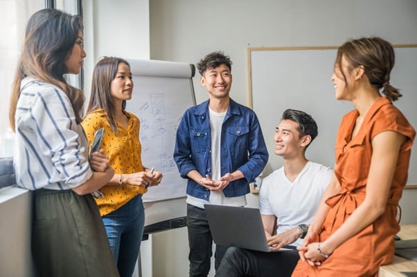 Group of young Asian professionals having a relaxed and cheerful team meeting in a bright modern office