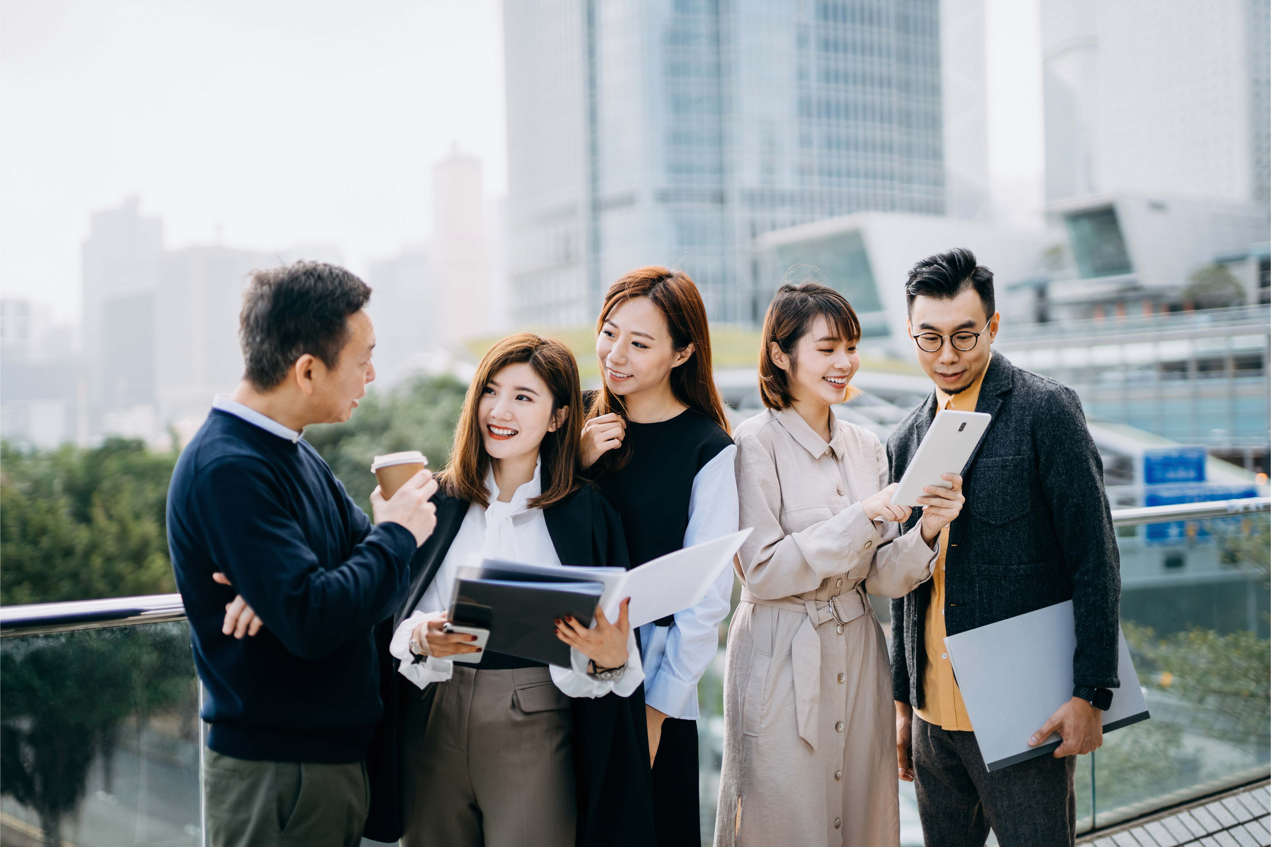 a group of male and female colleagues talking while standing