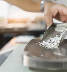 A jeweller pours uncut diamonds onto a scale