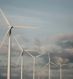 Five wind turbines on a hill against a clouded sky