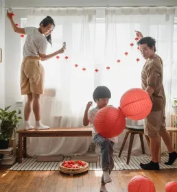 Family decorating their home with red lanterns and festive ornaments in preparation for Chinese New Year.