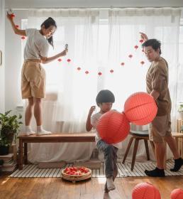 Family decorating their home with red lanterns and festive ornaments in preparation for Chinese New Year.