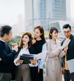a group of male and female colleagues talking while standing