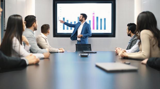 Financial advice presentation man showing graph to table full of people